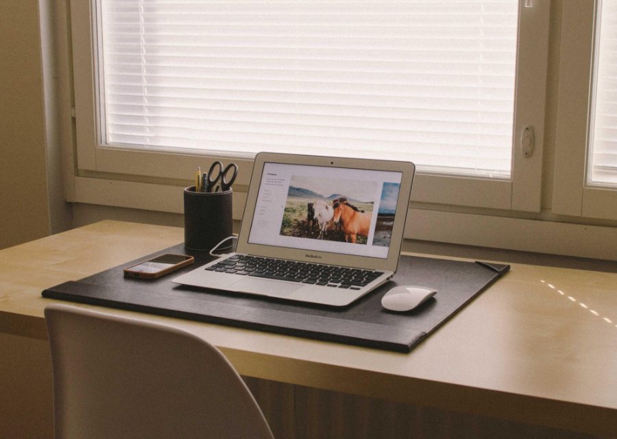A laptop open on a desk by a bright window